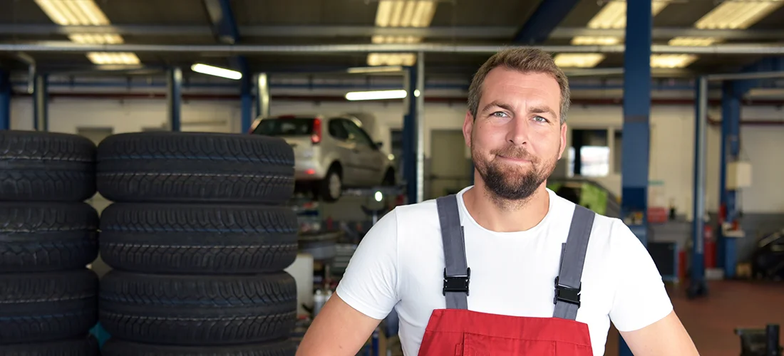 Foto von Mechaniker vor verschiedenen Autoreifen kurz vor der Reifeneinlagerung